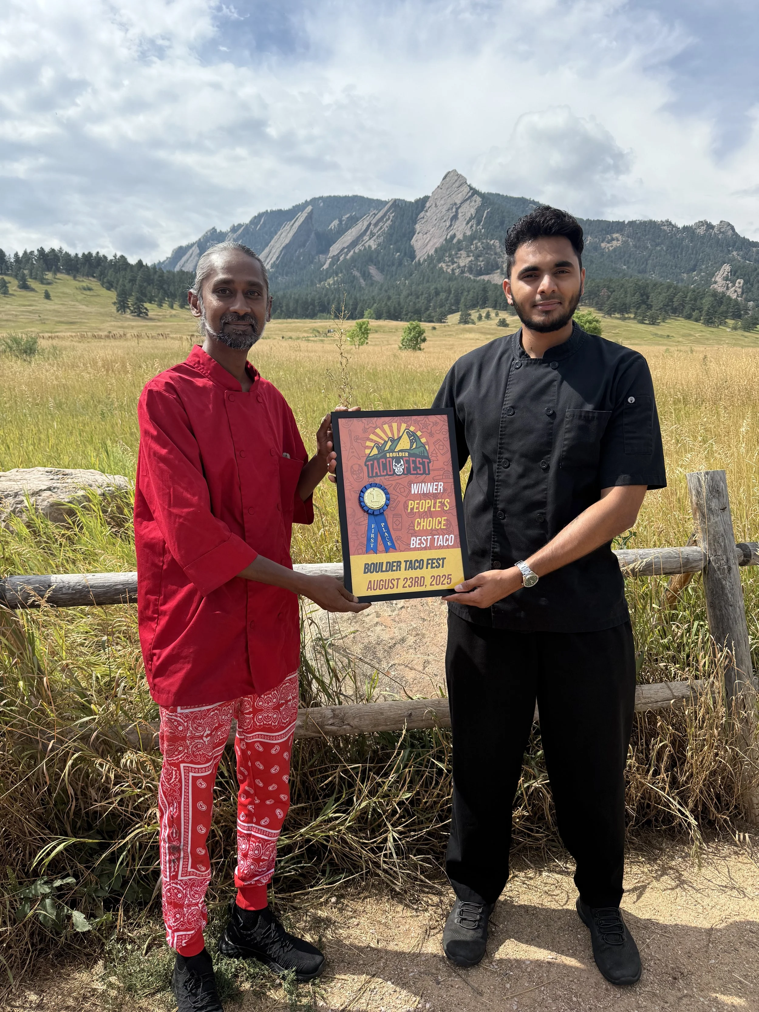Group holding a Boulder Taco Fest People's Choice Best Taco winner sign in front of a butterfly wing backdrop